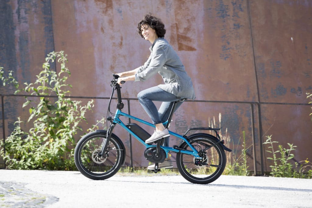 Eine Frau fährt mit dem Kompakt e-Bike Tinker von Riese und Müller durch die Stadt